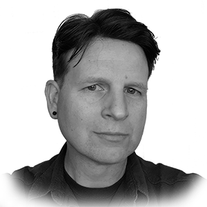 A picture of Thomas Karl. A decent looking fella of the caucasian persuasion with short,
         dark hair parted to the side. He is wearing black stud earrings and a black shirt. The picture is in grayscale.